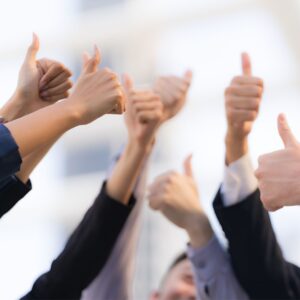 Glada medarbetare på en arbetsplats som pekar tummen upp